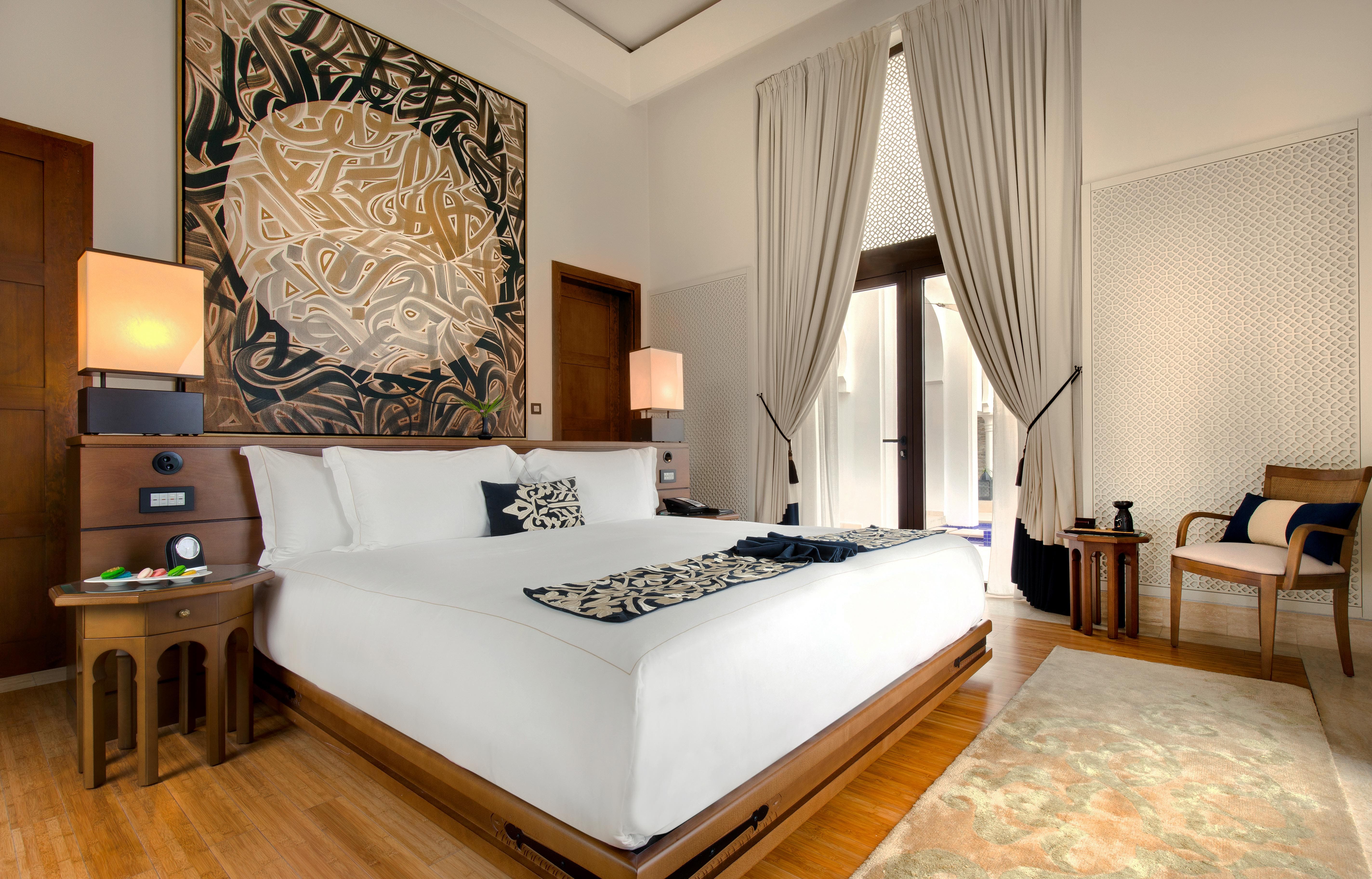 Luxurious Banyan Tree Tamouda Bay Harmony Pool Villa; bed with art above, chairs near window, elegant decor.